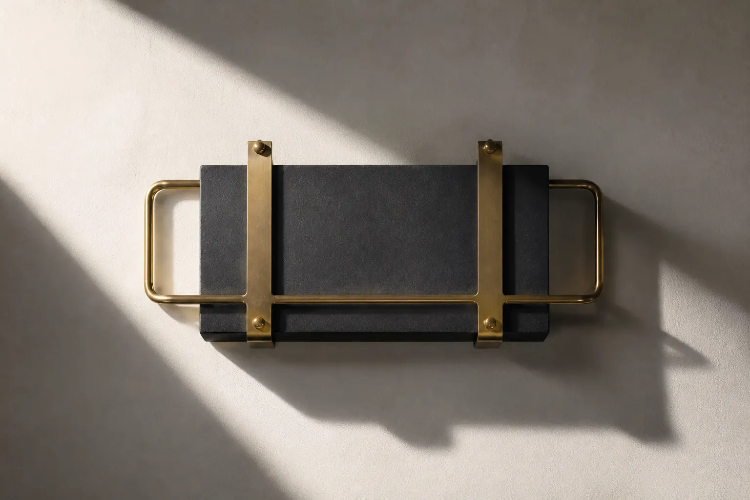 A charcoal block strapped in a brushed-brass frame with handle-like rods.