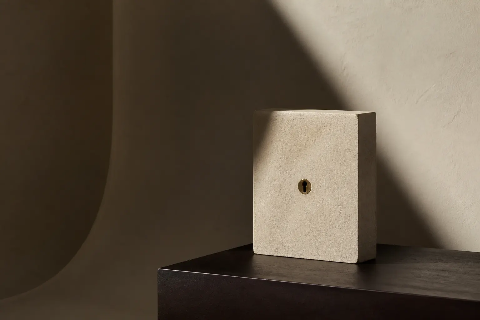 A beige stone block with a central brass keyhole, standing on a dark pedestal.